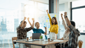 a group of people sitting around a table raising their hands