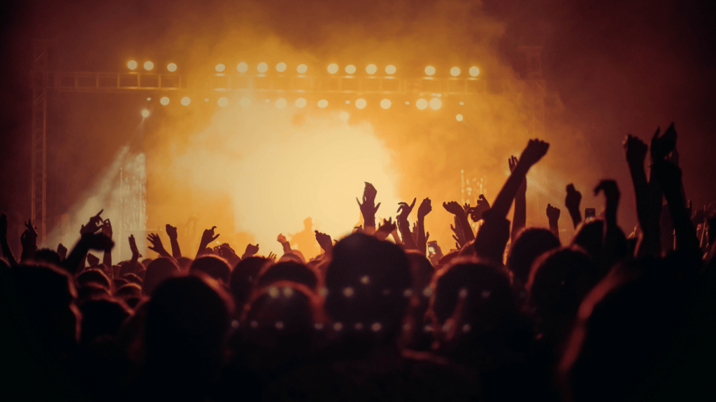 a crowd of people at a concert with their hands up in the air