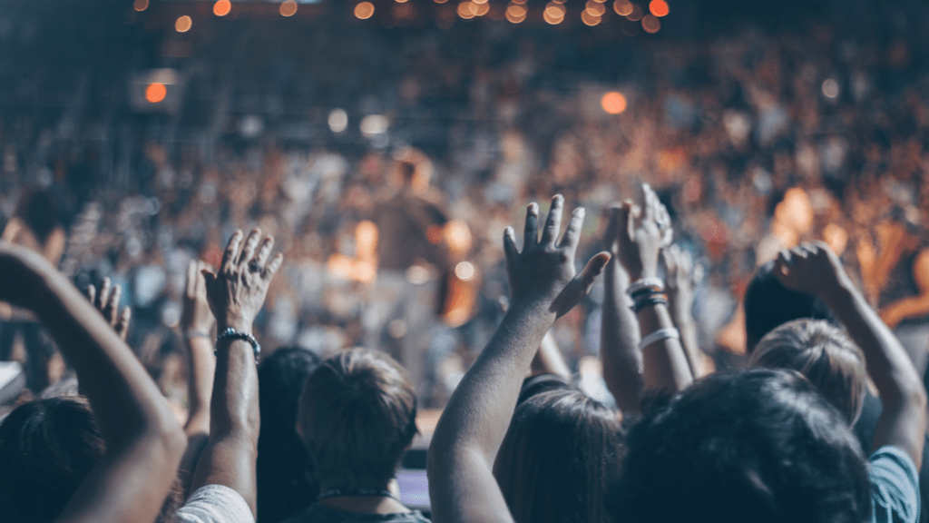 a crowd of people at a concert with their hands up in the air