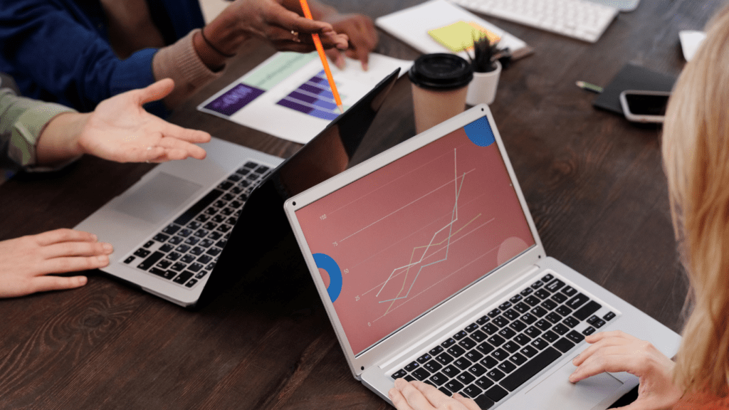 a group of people sitting around a table with laptops