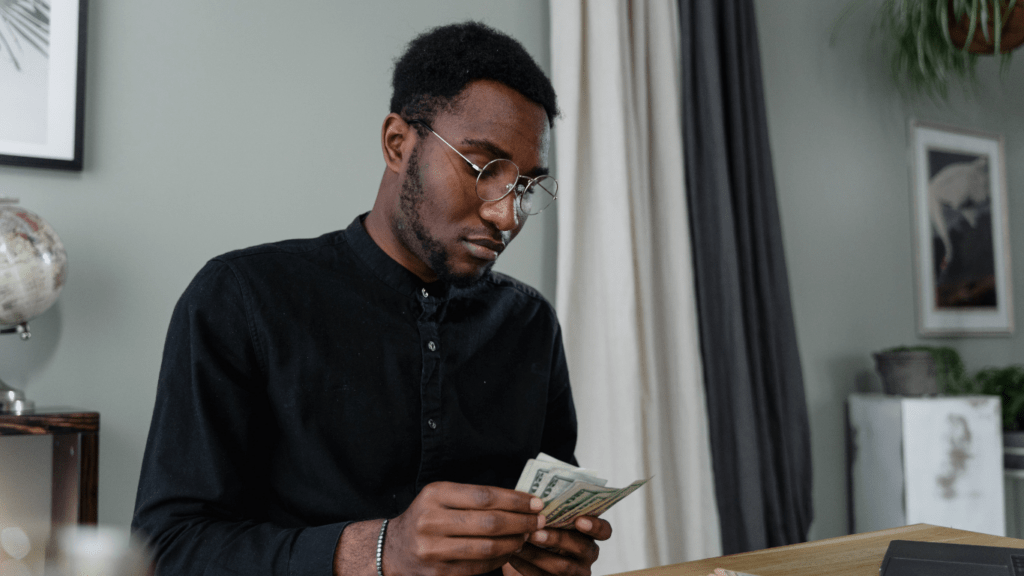 a person is holding money in front of a laptop