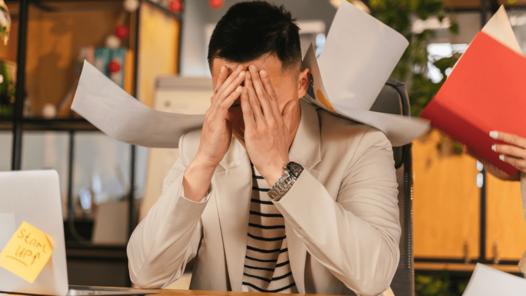 a person sitting at a table with their hands on their head