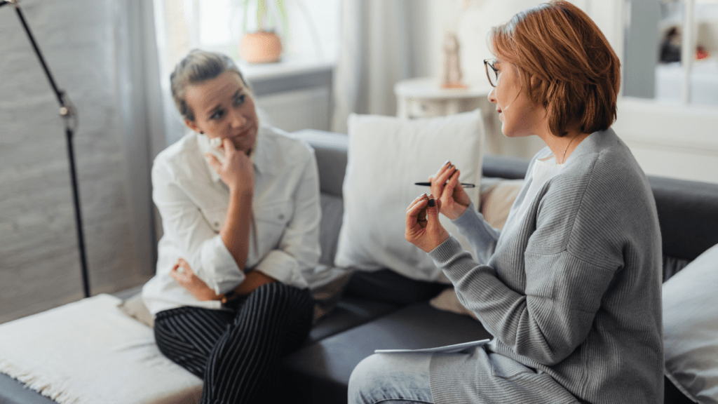 two people sitting on a couch talking to each other