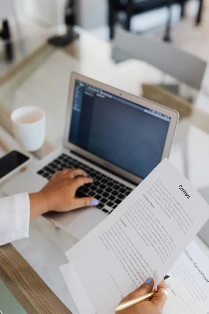 Person Holding a Document while Using Laptop